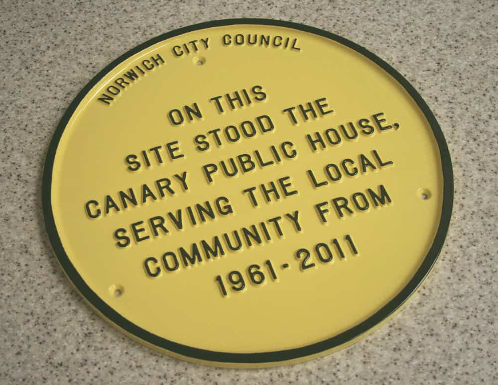 Cast metal commemorative wall plaque in yellow and black